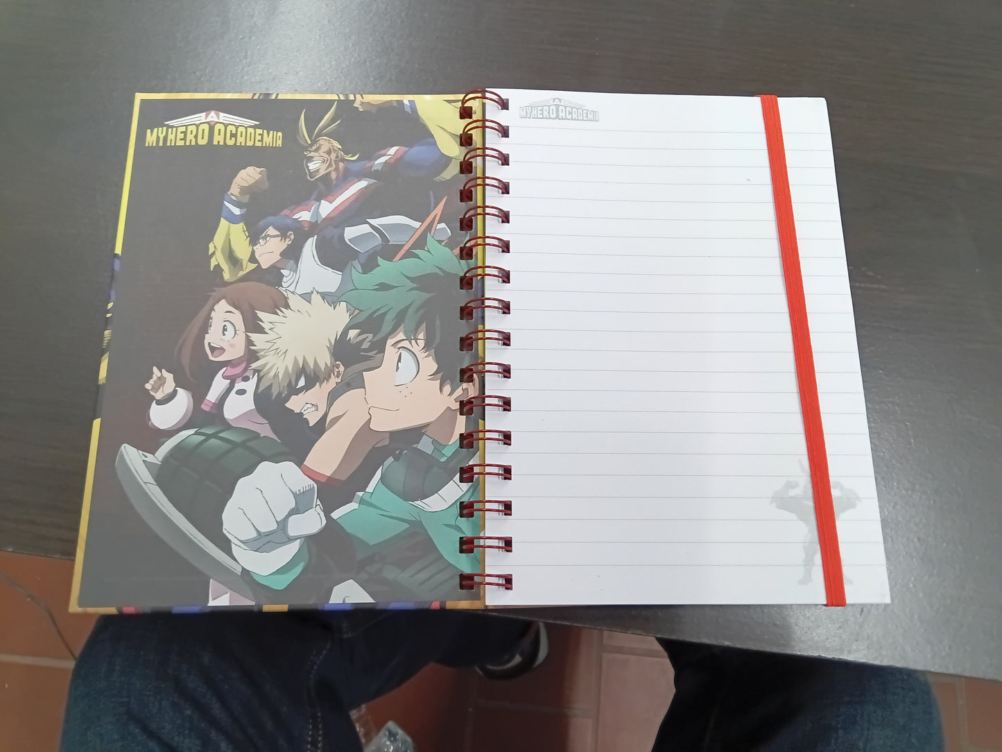 My Hero Academia spiral notebook open showing lined pages with red elastic band and interior artwork