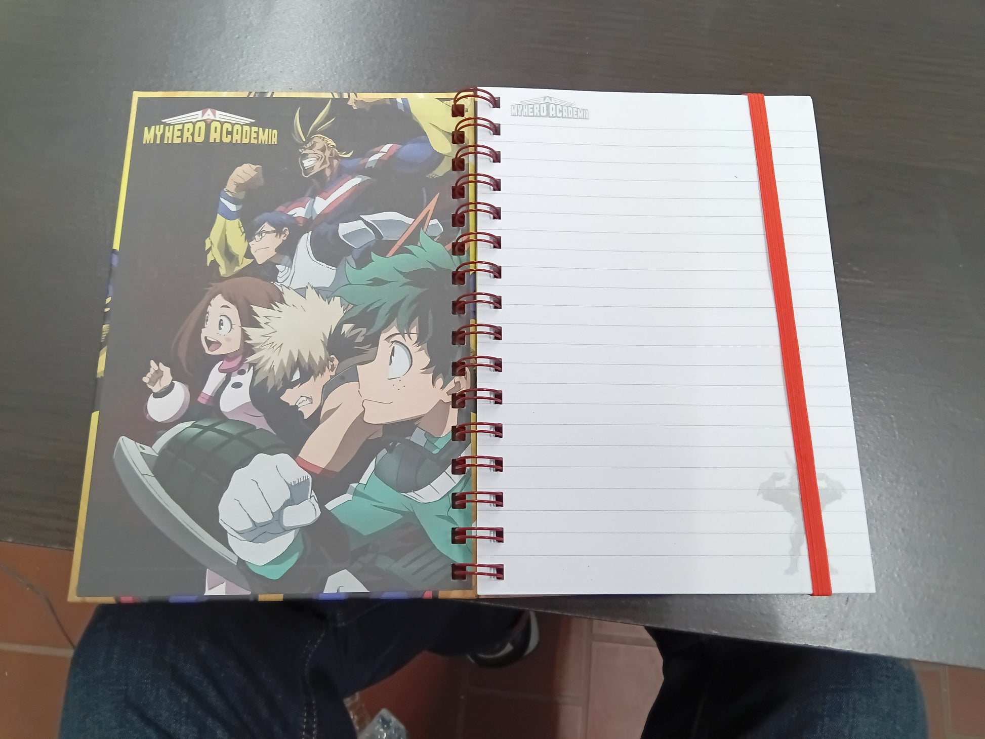 My Hero Academia spiral notebook open showing lined pages with red elastic band and interior artwork